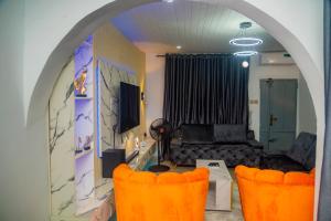 Budget Bliss Suites في بنين سيتي: غرفة معيشة مع كراسي برتقالية وأريكة