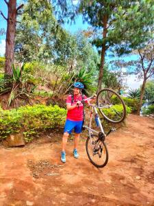 a man holding a bike on a dirt road at Camping Magamba Forest in Lushoto