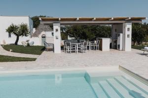 a swimming pool in front of a house with a patio at Borgo Chiancarosa, esclusivi trulli con piscina riscaldata in Putignano