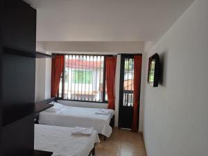 a hotel room with two beds and a window at SANTA HELENA HOSPEDERIA in Tibasosa +6 photos