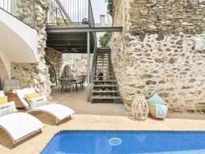 un patio al aire libre con piscina y pared de piedra en Belvilla by OYO Holiday home in Garriguella, en Garriguella