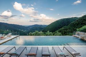 una piscina con sillas y montañas en el fondo en Villa Grema, a Farmhouse with Infinity Pool, en Loppeglia
