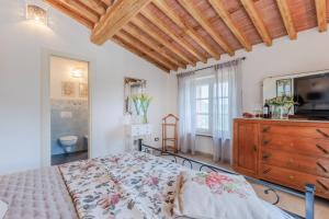 1 dormitorio con 1 cama y vestidor con TV en Villa Grema, a Farmhouse with Infinity Pool, en Loppeglia