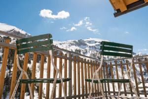 two green chairs sitting on a deck with snow covered mountains at Steinadler Gamsleiten FL - Skiing Holiday in Obertauern in Obertauern