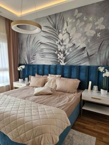 The One Apartment Fruške Residence في فردنيك: غرفة نوم مع سرير كبير مع اللوح الأمامي الأزرق