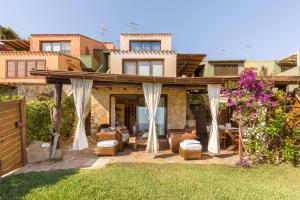 ヴィッラシミーウスにあるLuna Bay Home Retreat con vista sulla baia di Porto Luna a 2 km da Villasimiusの椅子とカーテンが備わったパティオのある家