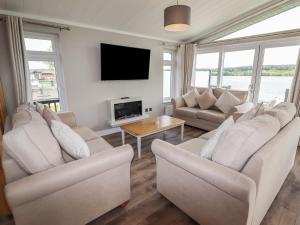 a living room with white furniture and a flat screen tv at 40 Delamere Point in Northwich