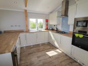 a kitchen with white cabinets and a wooden floor at 40 Delamere Point in Northwich