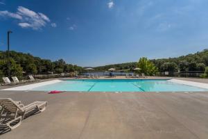 a large swimming pool with lounge chairs at Lakefront Branson Cabin 6 Mi to Branson Strip! in Branson West