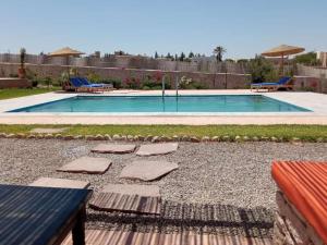 una piscina en un patio trasero con una mesa y un banco en Villa DAR MAMA, en Essaouira