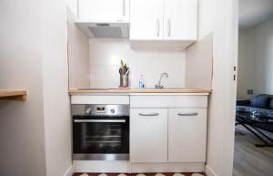 a kitchen with white cabinets and a sink and a stove at Superbe studio 2 pers tout équipé WIFI & Proche Paris - R2 in Montreuil
