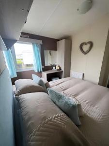 a bedroom with two beds with pillows and a heart on the wall at At The Waters Edge ( Wansbeck View 26 ) in Newbiggin-by-the-Sea