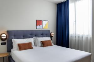 a bedroom with a large white bed and blue curtains at The Poet Hotel in La Spezia