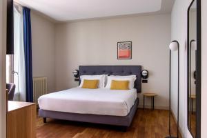 a bedroom with a large white bed with yellow pillows at The Poet Hotel in La Spezia