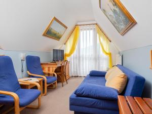 a living room with blue chairs and a desk at Hotel Jan in Szczawnica
