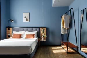 a bedroom with blue walls and a bed with orange pillows at The Poet Hotel in La Spezia