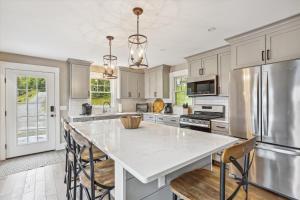 a kitchen with a large white island with chairs in it at The Sperry House in Stowe