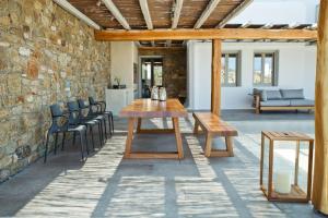 un patio con mesa de madera y sillas en Super Luxury Mykonos Villa - Villa La Isla Bonita - Private Gym - Private Pool - 5 Bedrooms - Sea Views en Dexamenes