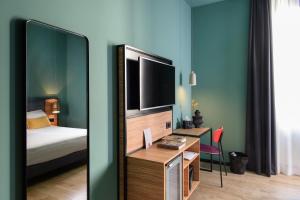 a room with a bed and a desk with a television at The Poet Hotel in La Spezia