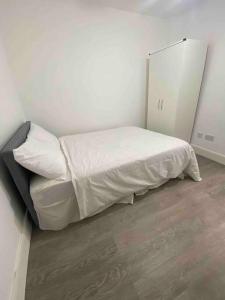 1 dormitorio pequeño con 1 cama con sábanas blancas en Gladys’ Apartment, en Ponders End