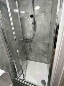 cabina de ducha con puerta de cristal y ducha en Gladys’ Apartment, en Ponders End
