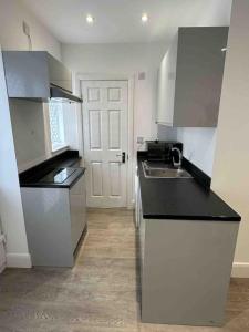 a kitchen with a black counter top and a sink at Gladys’ Apartment in Ponders End