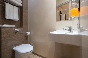 bagno con lavandino, servizi igienici e specchio di Simply Rooms & Suites a Londra