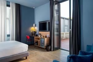 a bedroom with a bed and a desk with a television at The Poet Hotel in La Spezia