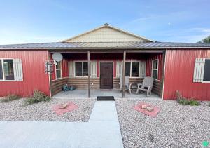 un edificio rojo con un patio con mesa y sillas en Pinyon View Murdock Cabin en Verdure