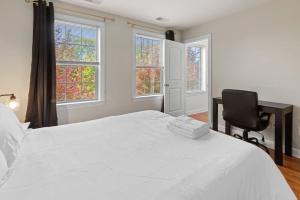 a bedroom with a white bed and a chair and windows at Affordable 2-BR Heart of Detroit in Detroit