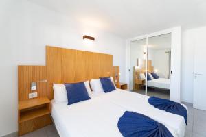 ein Schlafzimmer mit einem großen weißen Bett mit blauen Kissen in der Unterkunft Ereza Apartamentos Los Hibiscos - Adults Only in Puerto del Carmen + 45 Fotos
