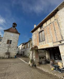 a building with a clock tower and two people sitting at a table at Les Mirabelles in Tournon-dʼAgenais