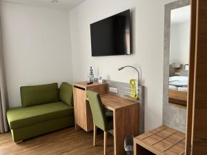 een woonkamer met een bureau en een groene stoel bij Hotel Knotenpunkt in Meppen