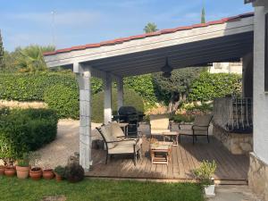 een pergola met stoelen en een grill op een terras bij Nice holiday house with pool at La Sella Golf between Denia and Javea in Pedreguer