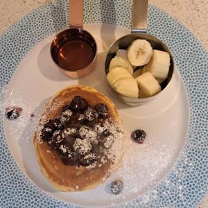 a plate with a pancake and a bowl of fruit at Waterfront House in Dartmouth