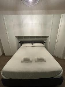 Una cama blanca con dos toallas encima. en Green Apartment, en Pioltello