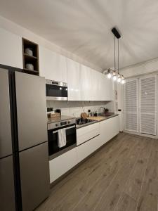 a kitchen with white appliances and a wooden floor at Green Apartment in Pioltello