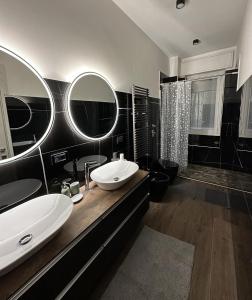 Baño en blanco y negro con 2 lavabos y espejos en Green Apartment en Pioltello