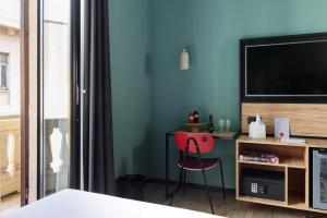 a room with a desk with a television and a red stool at The Poet Hotel in La Spezia