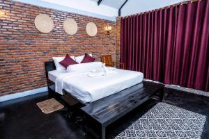 Bat Rice Resort في باتامبانغ: غرفة نوم بسرير وجدار من الطوب