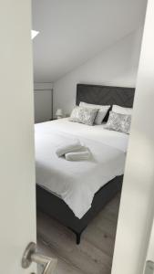 um quarto com uma cama grande com lençóis brancos e almofadas em Apartman Polaris Posušje em Posušje
