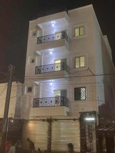 un edificio alto y blanco con gente parada frente a él en RÉSIDENCE NGUARY en Dakar