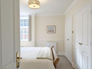 a white bedroom with a bed and a window at 5 The Clock House in Midhurst