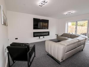 a white living room with a couch and a tv at Maritos in Holywell