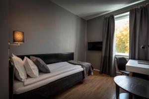 een slaapkamer met een bed, een bureau en een raam bij Hotell Skövde in Skövde