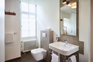 ein Bad mit einem Waschbecken, einem WC und einem Fenster in der Unterkunft Gutshotel Baron Knyphausen in Eltville