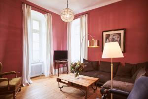 a living room with red walls and a couch and a table at Gutshotel Baron Knyphausen in Eltville