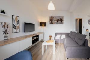 a living room with a couch and a tv at Gîte de la Place classé 3 étoiles Centre Bourg WIFI Services prosConciergerie Comte des Cierges 