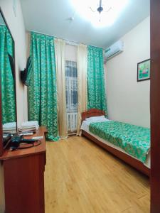 a room with a bed and a window with green curtains at Hotel Zavq in Andijan