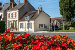 a house with red flowers in front of a street at Gîte de la Place classé 3 étoiles Centre Bourg WIFI Services prosConciergerie Comte des Cierges 